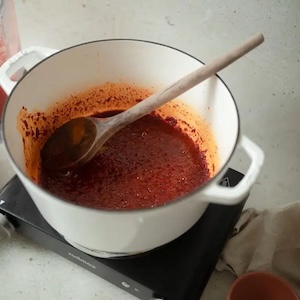 jollof stew in a pot with a wooden spoon